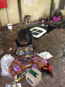 Marrnyula Mununggurr works on her series of pendants with her mother Nongirrnga Marawili painting behind her